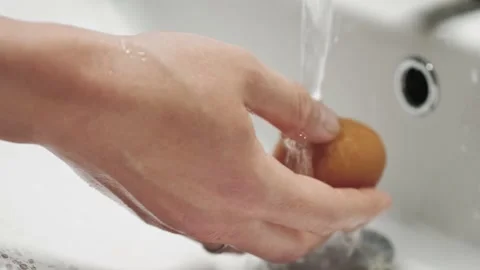 Close-up of hands wash the egg with soap under running water. Stock Footage 131521127