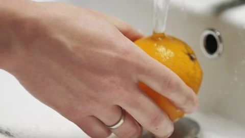 Close-up of hands wash the orange under running water. Stock Footage 131876465