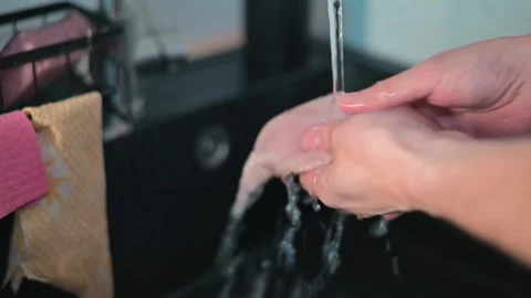 Close-up of hands washing chicken breast fillets in the kitchen, food hygiene Stock Footage 338301311