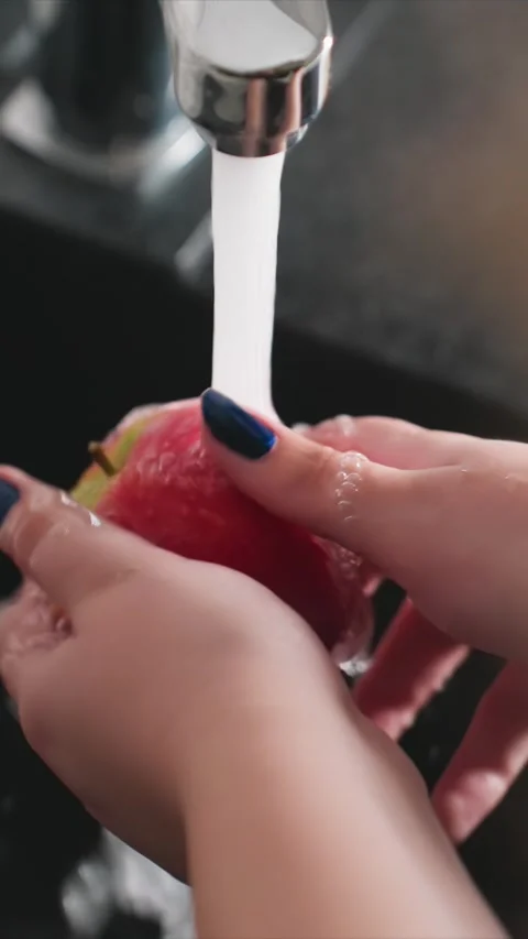 Close up of hands washing red apple under running water in kitchen sink with Stock Footage 346782493