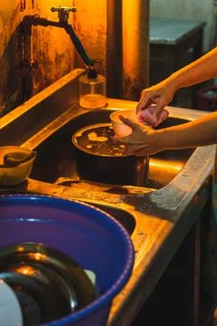 Close-up of hands washing a small plastic bowl at a kitchen sink 库存照片