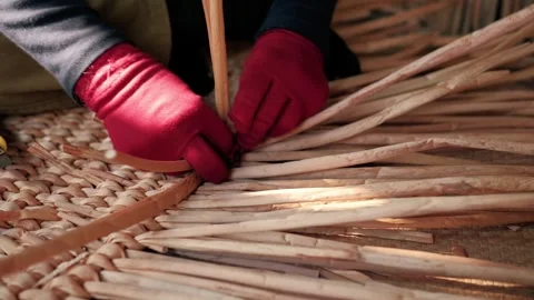 Close up of hands weaving a traditional mat using natural plant fibers in a Stock Footage 325975191