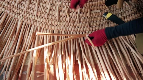 Close up of hands weaving a traditional mat using natural plant fibers in a Stock Footage 325975216