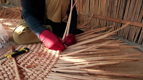 Close up of a hands weaving a traditional straw mat. Cambodian woman crafting a Stock Footage 325974703