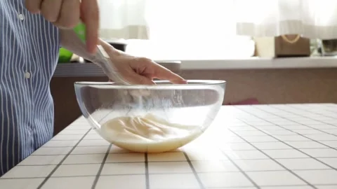 Close up of hands whisking eggs in transparent glass bowl on kitchen table,.. Stock Footage 318296679