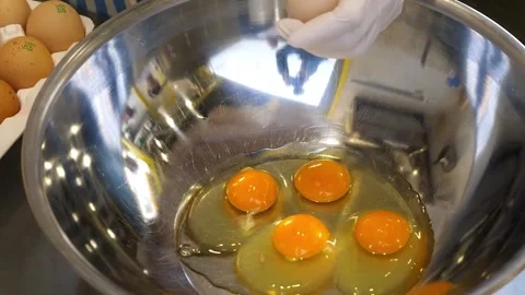 Close-Up of Hands in White Gloves Breaking and Separating Raw Chicken Eggs into Stock Footage 331772313
