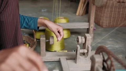 Close up of a hands winding silk thread onto a bobbin using a manual wooden Stock Footage 325974440