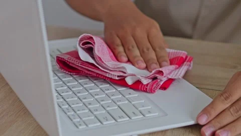 Close-up of hands wiping dust off laptop using microfiber rag in bright office Stock Footage 335483301