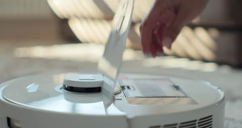 Close-up hands of woman opens tank of robot vacuum cleaner after cleaning and Stock Footage 252176771