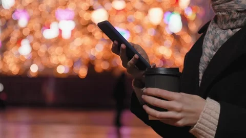 Close-up hands of woman using smartphone and holding cup of coffee city lights Stock Footage 280272710
