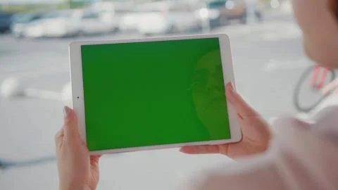 Close up hands woman using tablet device computer with green screen outdoors in Stock Photos