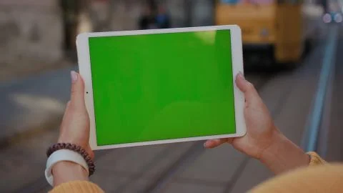 Close up hands woman using tablet device computer with green screen outdoors in Stock Photos
