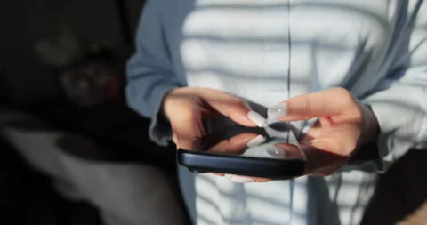 Close-up of hands of woman writes a text message on smartphone in the living Stock Footage 335884874
