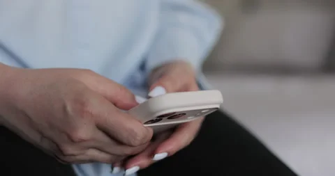 Close-up of hands of woman writes a text message on smartphone in the living Stock Footage 335885341