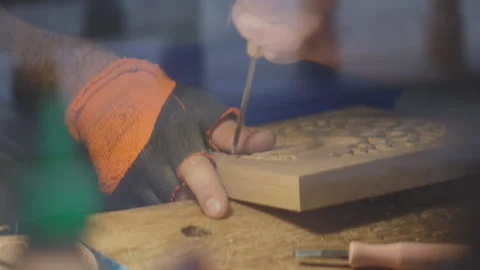 Close up hands of a wood carver using a small chisel to make a relief carving Stock Footage 240696232