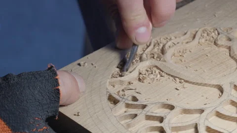 Close up hands of a wood carver using a small chisel to make a relief carving Stock Footage 240696937