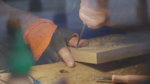 Close up hands of a wood carver using a small chisel to make a relief carving Stock Footage 240697677
