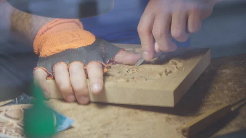Close up hands of a wood carver using a small chisel to make a relief carving Stock Footage 240697708