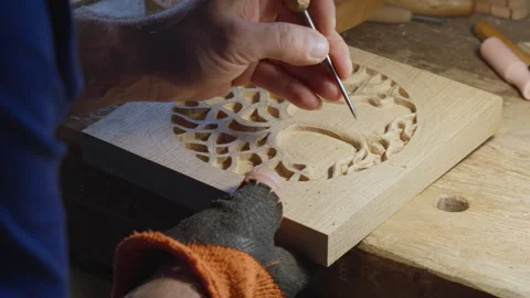 Close up hands of a wood carver using a small chisel to make a relief carving Stock Footage 240698087