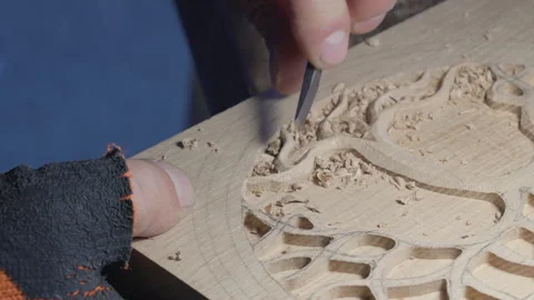 Close up hands of a wood carver using a small chisel to make a relief carving Stock Footage 240698143