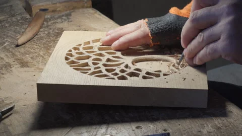 Close up hands of a wood carver using a small chisel to make a relief carving Stock Footage 240698505
