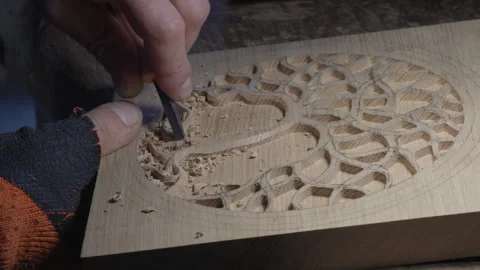 Close up hands of a wood carver using a small chisel to make a relief carving Stock Footage 240698776