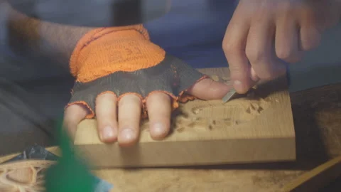 Close up hands of a wood carver using a small chisel to make a relief carving Stock Footage 240699287