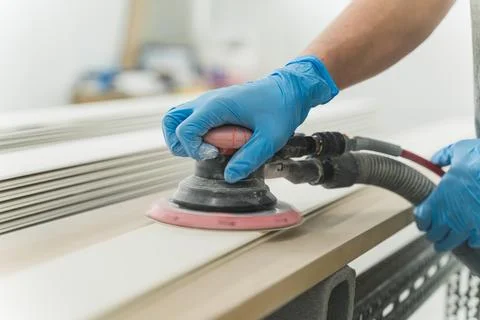 Close-up hands of worker with gloves using electric sander in workshop. Joiner Stock Photos