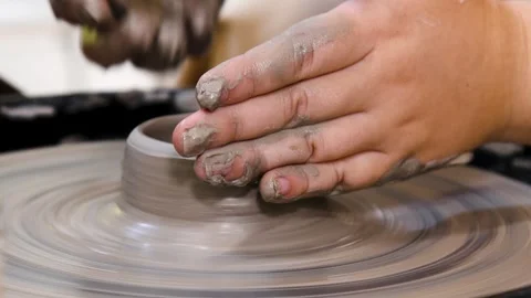 Close-up of hands working with clay on a potter's wheel in a pottery studio.. 库存影片 339765079