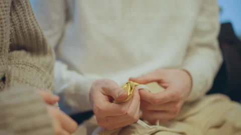 Close up of hands working with golden thread and beige knitted fabric Stock Footage 347982027