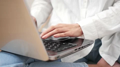 Close-up of hands working on a laptop laptop. The girl is sitting on the flo Stock Footage 186235864