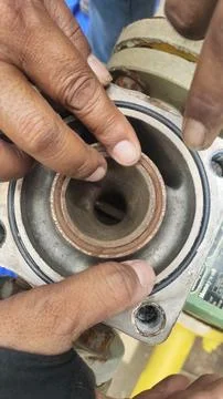 Close-up of hands working on a mechanical component, likely for maintenance.. Stock Photos