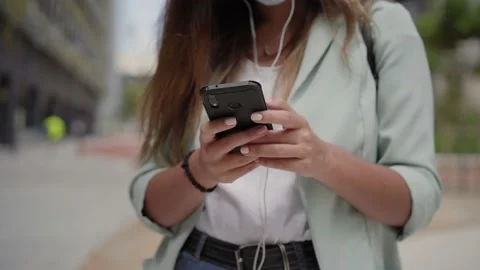 Close-up of the hands of a working woman wearing facial mask with a smartphon Stock Footage 139650053