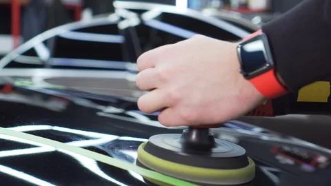 Close-up of hands of workshop worker, he is busy polishing hood of expensive car Stock Footage 115933865