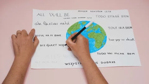 Close-up of hands writing all will be ok in earth-inspired drawing Stock Footage 277518562