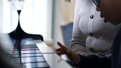 Close Up Of Hands As Young Boy Learns To Play Piano Having Lesson From Female Stock Footage