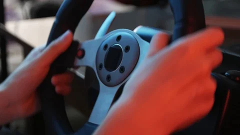 Close-up of the hands of a young gamer behind the steering wheel of a racing  Stock Footage 113546742