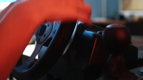 Close-up of the hands of a young gamer behind the steering wheel of a racing  Vidéo 113546771