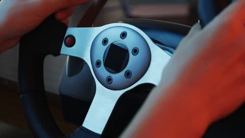 Close-up of the hands of a young gamer behind the steering wheel of a racing  Stockbeeldmateriaal 113546822