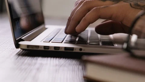 Close-up of hands of a young man typing on a laptop keyboard, finishing work and Stock Footage 104154108