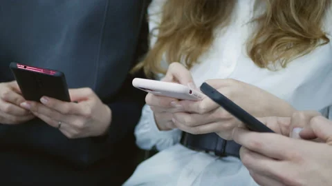 Close-up of hands of young people typing with phones for messages in social net Stockbeeldmateriaal 124119729