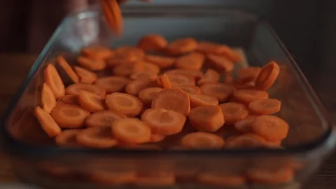 Close-up of hands of a young woman laying chopped carrots in a large glass bowl Stock Footage 127509853