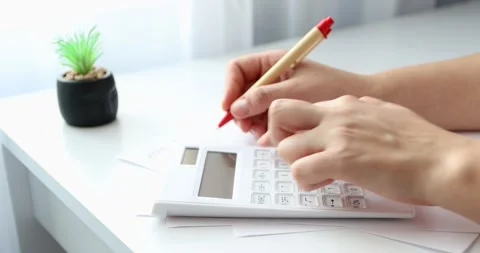 Close-up of hands young woman using calculator and paper documents for financ Stock Footage 300364050