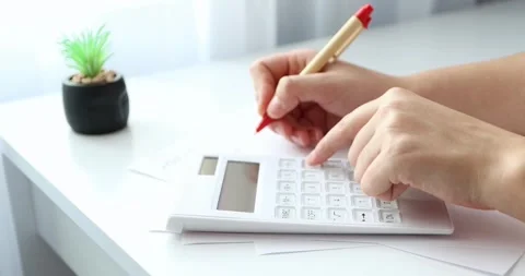 Close-up of hands young woman using calculator and paper documents for financ Stock Footage 300364064