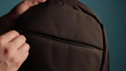 Close-up of hands zipping up a dark brown backpack pocket Stock Footage 340265826