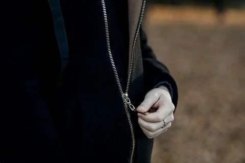 Close-up of hands zipping up a jacket. Stock Photos