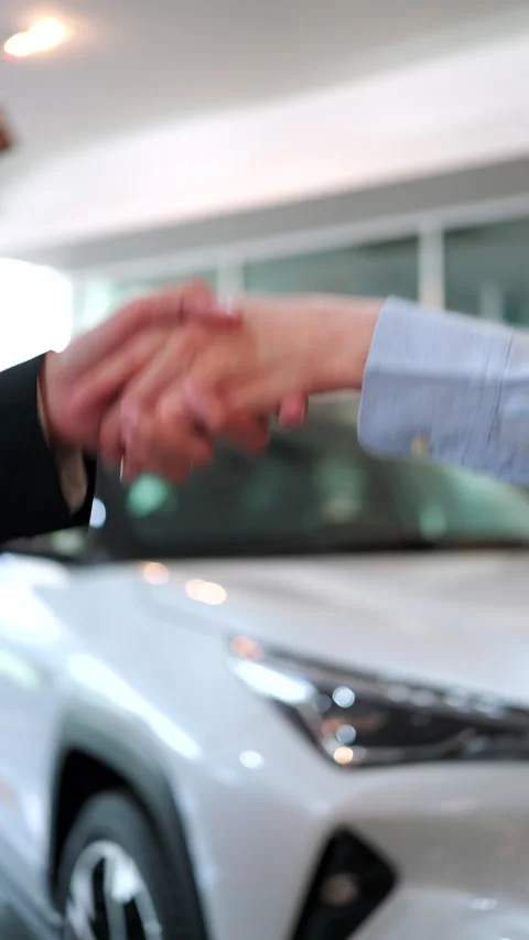 Close-up handshake between a car dealer and a buyer after signing a contract. Stock Footage 346268802