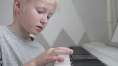 Close-up, handsome blonde boy learns to play the electronic piano Stock Footage 145414131
