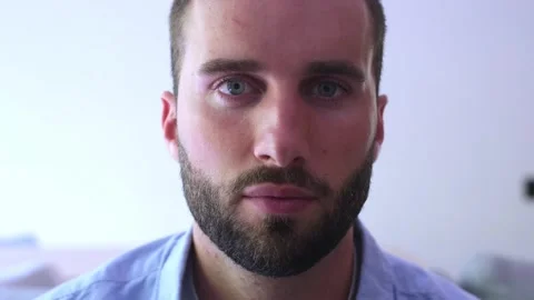 Close-up of a handsome caucasian man with a beard and blue eyes opening his Vídeos de archivo 344757143