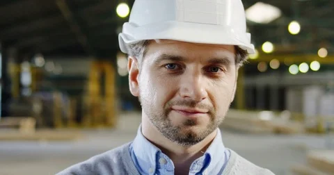 Close up of handsome engineer in a helmet posing and smiling to the camera at Stock Footage 84411541